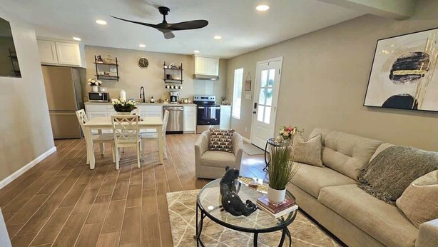 A living room with a sofa, coffee table, and a dining area with chairs and a table.