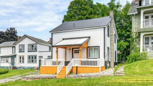 Ein modernes, zweistöckiges Haus mit Veranda, kleiner Treppe und gepflegtem Rasen.