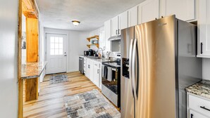Eine moderne Küche mit weißen Schränken, einem Edelstahlkühlschrank und einer Wand mit Holzverkleidung.