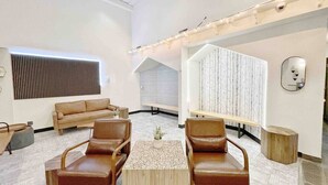 A modern lounge area with leather chairs, a wooden coffee table, and a large wall-mounted light fixture.