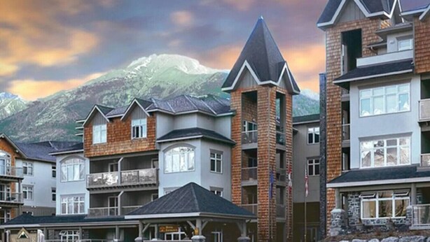 A row of modern multi-story buildings with a mountain backdrop.