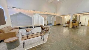 Un hall d’entrée spacieux avec un espace salon central, un comptoir d’accueil et un sol recouvert de carreaux de pierre.