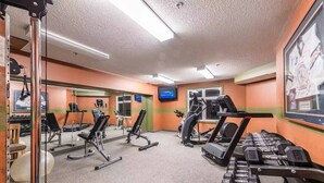 Une salle de sport équipée de tapis de course, de vélos elliptiques et de bancs de musculation.