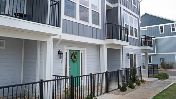 A multi-story residential building with a green door, white trim, and black railings. - Modern 3BR Retreat | Mtn Views & Garage Parking (South Salt Lake)