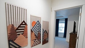 A hallway with three wooden wall art pieces depicting mountain scenes. - Modern 3BR Retreat | Mtn Views & Garage Parking (South Salt Lake)