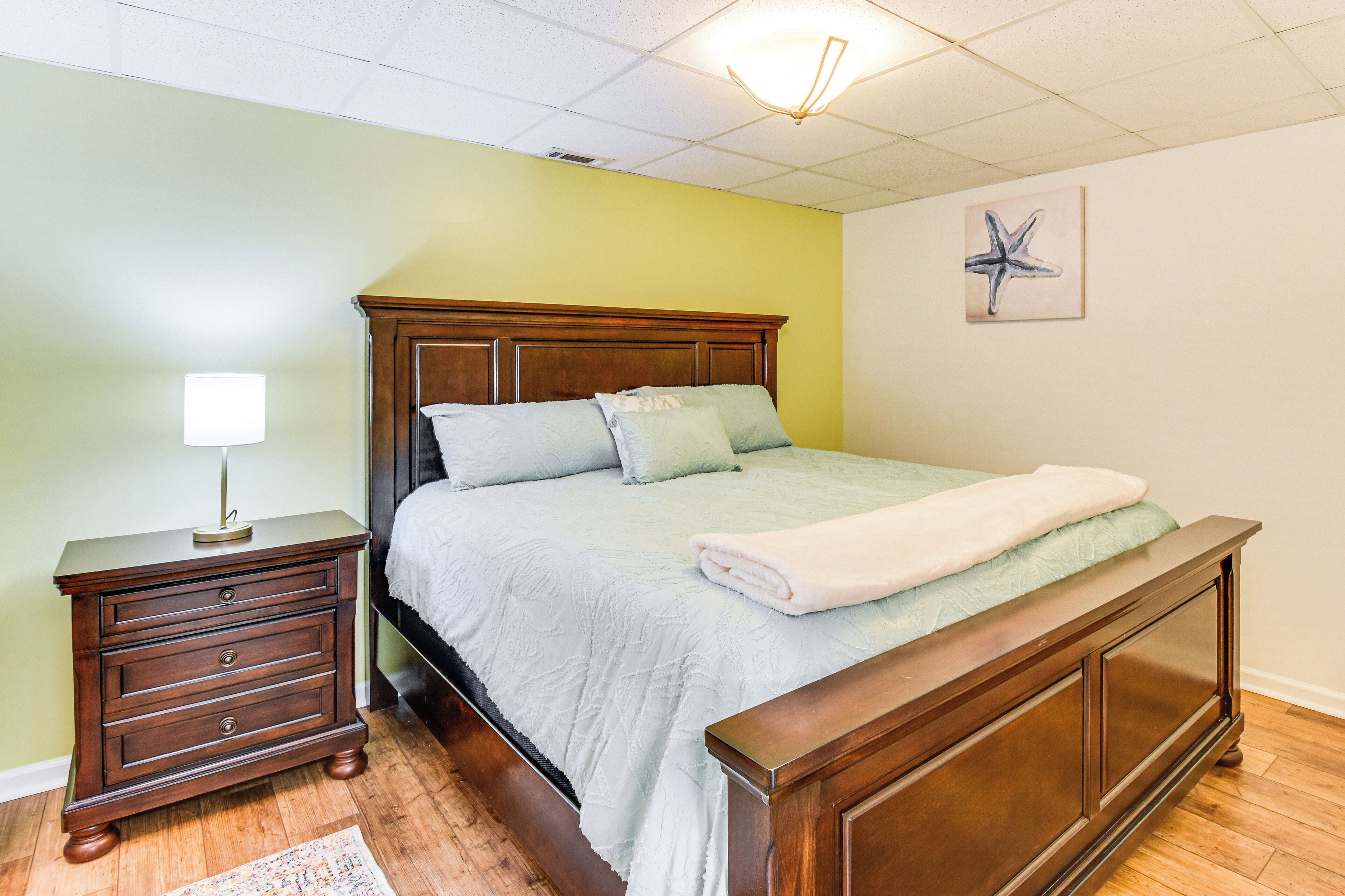 A bedroom with a wooden bed, a nightstand, and a wall-mounted lamp.