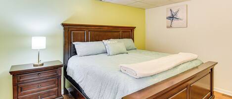 A bedroom with a wooden bed, a nightstand, and a wall-mounted lamp.
