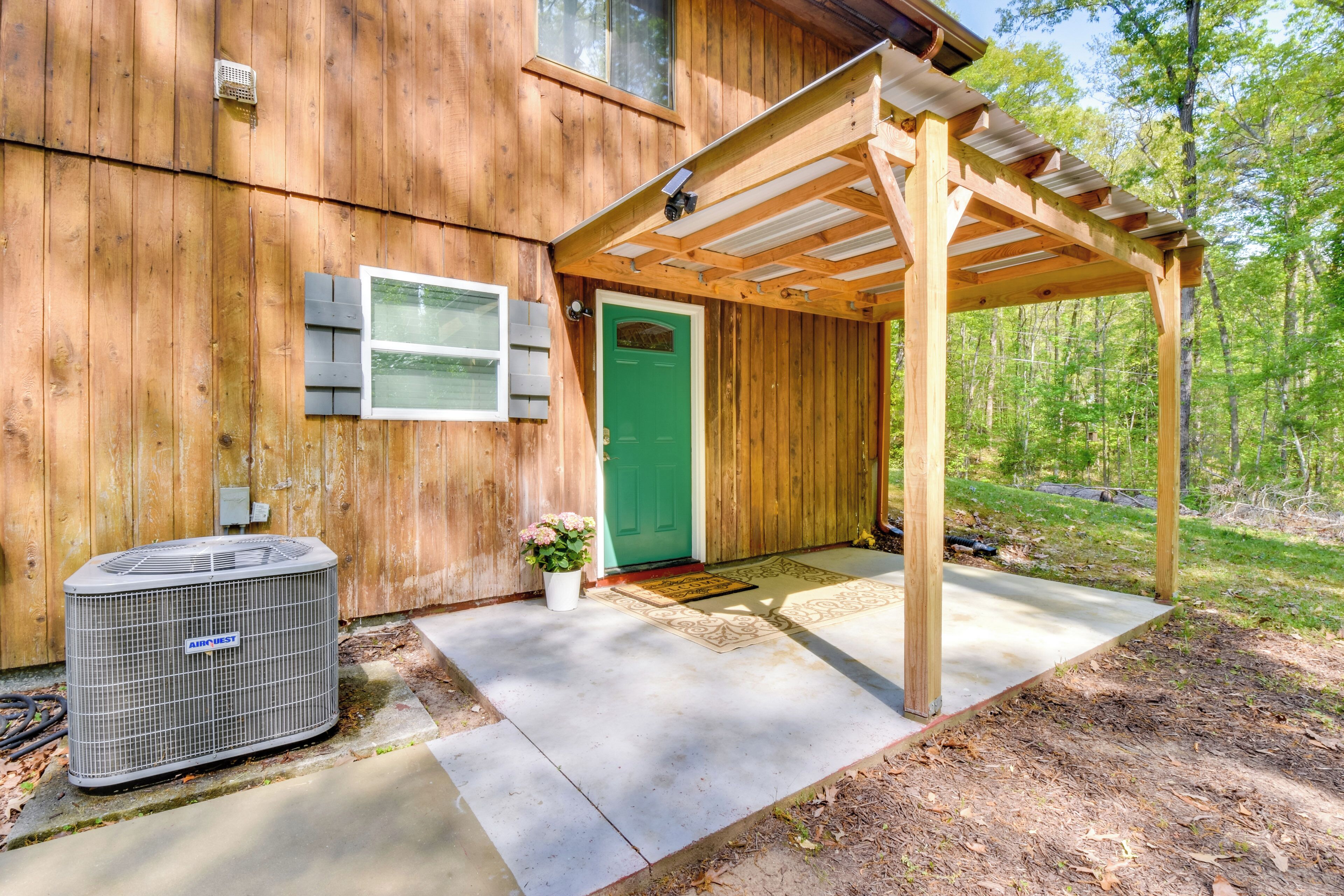 A wooden house with a green door, a covered porch, and an air conditioning unit.