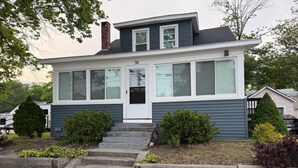 Une maison à deux étages avec un porche à l’avant, une cheminée et une boîte aux lettres.