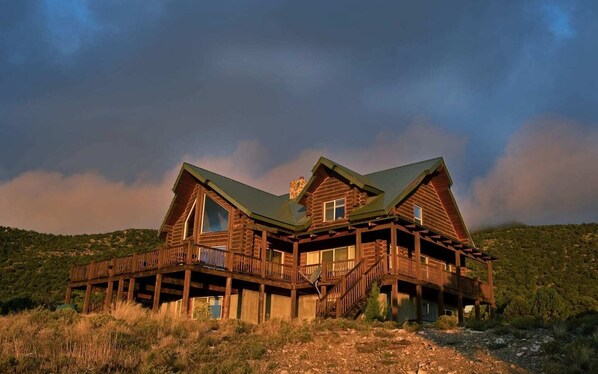 Une grande cabane en rondins dotée de nombreux balcons et d’un toit à forte pente, entourée d’un paysage naturel.