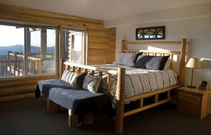 Une chambre dans une cabane en bois, avec un lit, un banc et une table de chevet.