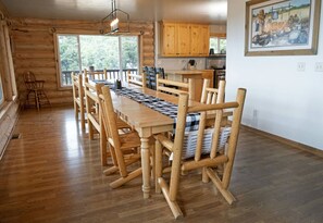 Un intérieur en bois avec une longue table à manger et des chaises, des meubles en bois et un tableau accroché au mur.