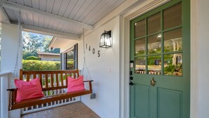 A porch with a wooden swing, a green door, and a house number 1405. - Spacious 4BD - Central Stay w/ Backyard & Games (Tallahassee)
