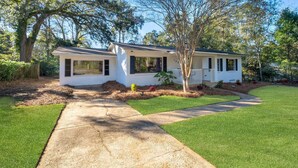 A single-story house with a front porch, a small deck, and a well-maintained lawn. - Spacious 4BD - Central Stay w/ Backyard & Games (Tallahassee)