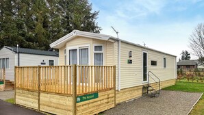 A mobile home with a wooden deck and a sign reading "The Kestrel."