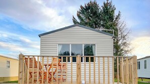 A single-story mobile home with a fenced deck, a window, and a metal roof.