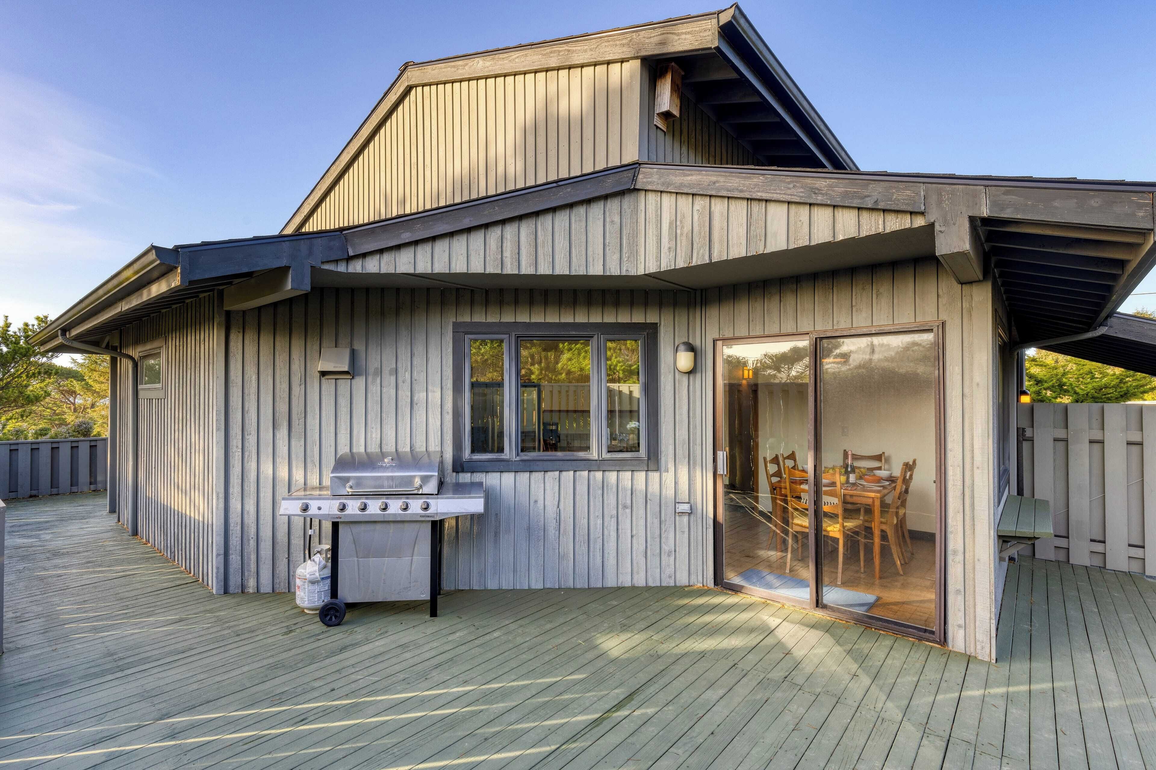 A modern house with a wooden exterior, a covered patio, and a barbecue grill.