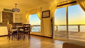 En matplats med ett bord och stolar, en kristallkrona och utsikt över stranden genom stora fönster.