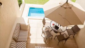 Un patio con piscina, cojines a rayas y una mesa con sillas.