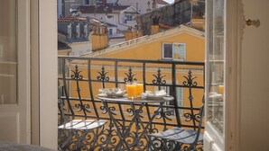 A balcony with a table and chairs, a view of buildings, and a door.