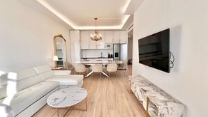 A modern living room with a sofa, a round coffee table, and a TV mounted on the wall.
