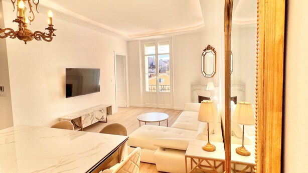 A modern living room with a marble dining table, a sofa, and a TV.