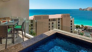 A balcony with a view of the ocean, a pool, and a dining area with chairs and a table. - Chic 2-bedroom deluxe suite. A few steps away from Medano Beach!! CABO SAN LUCAS (Cabo San Lucas)