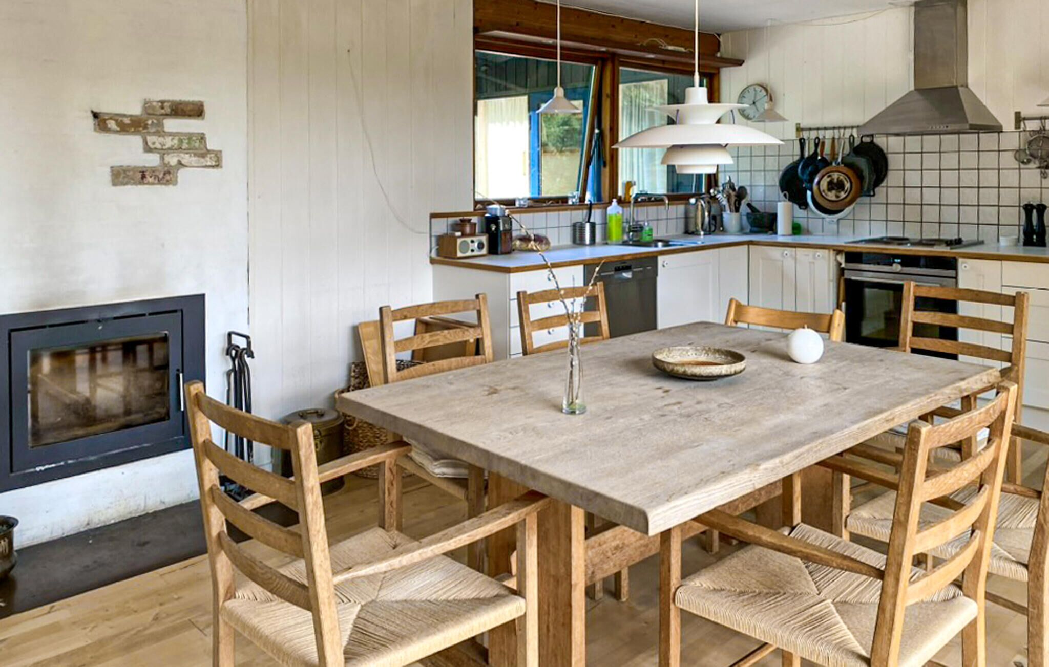 Ein Essbereich mit Holztisch und -stühlen, einem Kamin und einer Küche im Hintergrund.