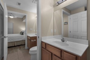A bathroom with a large mirror, a sink, and a toilet. There is a door leading to a bedroom with a bed and a window. - Gulf Views-Short Walk 2 Beach-Resort Amenities (Miramar Beach)