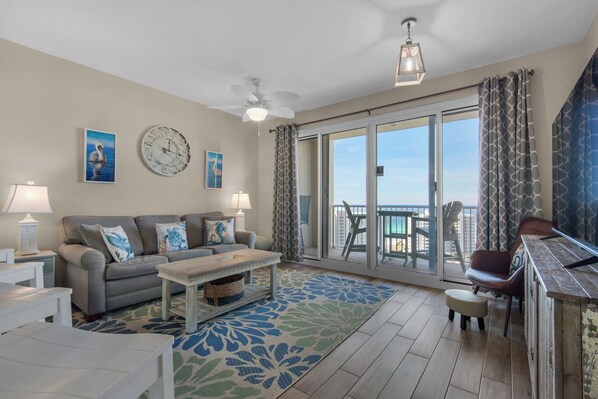 A living room with a sofa, coffee table, and a view of the balcony. - Gulf Views-Short Walk 2 Beach-Resort Amenities (Miramar Beach)
