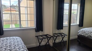 A bedroom with a bed, a small table, a mirror, and a window with curtains. - Cozy Cottage, 2-bedroom duplex in delightful Beach City with WiFi, AC (Torrance)