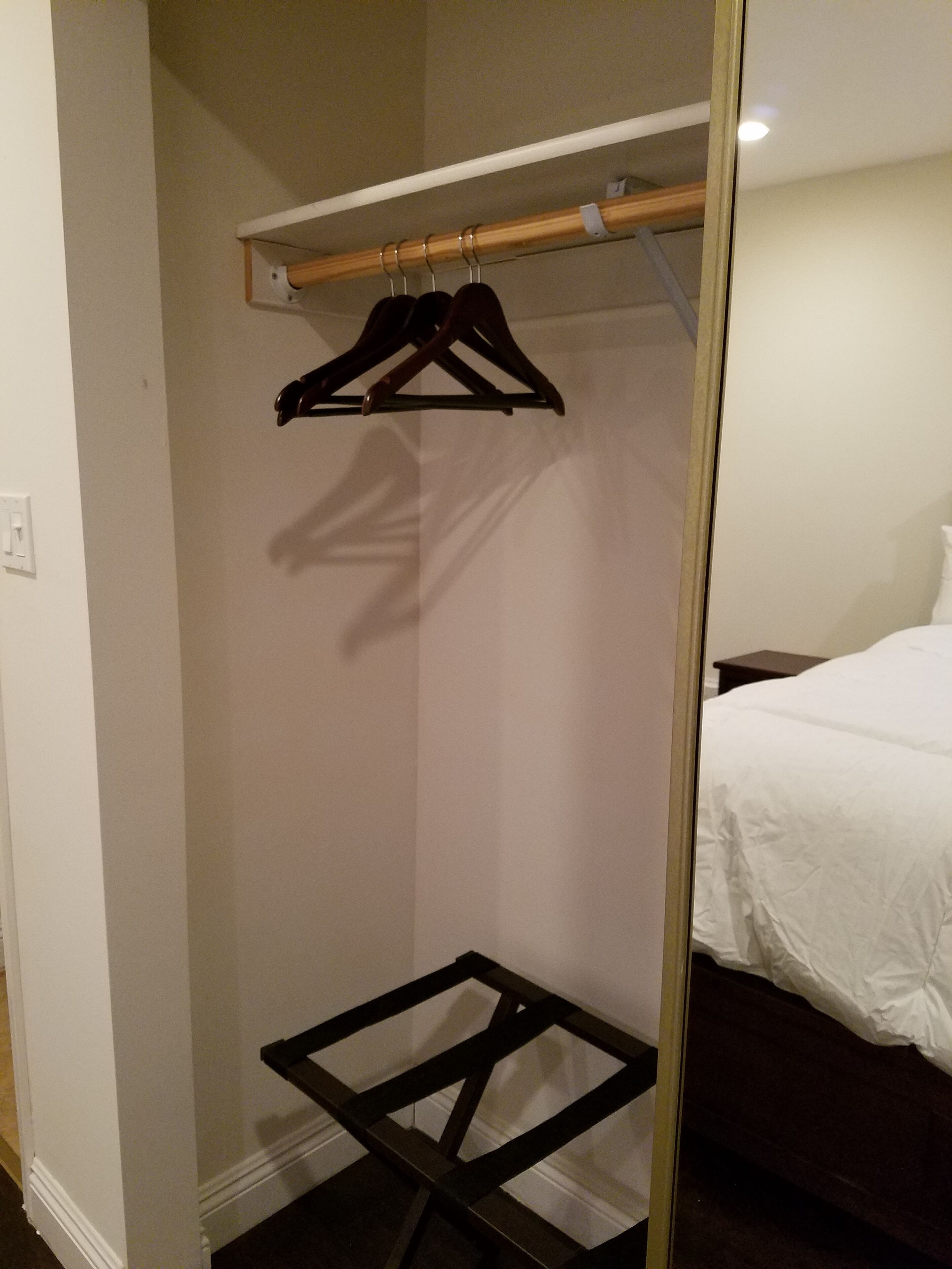 Ein Schlafzimmer mit einem Bett, einem Holzschrank mit Kleiderstange und einem kleinen schwarzen Tisch.