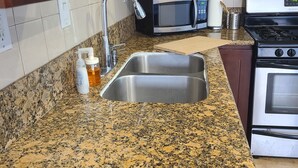 A kitchen with granite countertops, stainless steel appliances, and wooden cabinets. - Cozy Cottage, 2-bedroom duplex in delightful Beach City with WiFi, AC (Torrance)