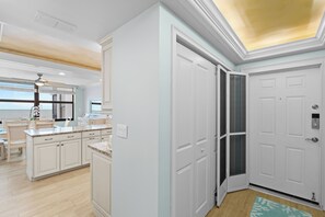 Une cuisine moderne avec des meubles blancs, un four encastré et un grand îlot central doté de sièges.