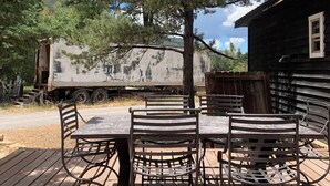 A wooden deck with a table and chairs, a tree, and a building with a window. - Spacious 4 bd 2 bth Ridgway-Ouray Ranch Home; Adventure Basecamp! STR-1-2024-069 (Ridgway)