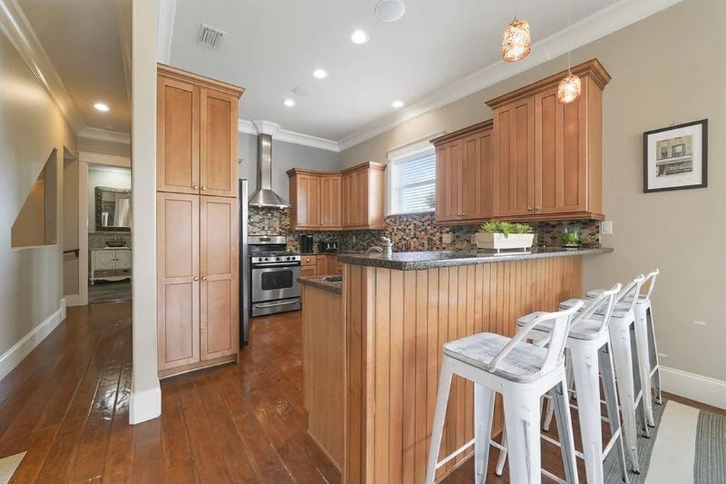 A kitchen with wooden cabinets, a central island with bar stools, and a stainless steel range hood.