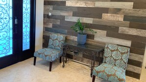 A reception area with a modern design, featuring a herringbone-patterned wall and two patterned chairs.