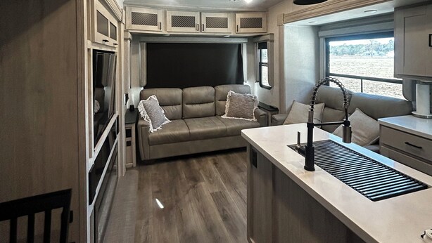 Un intérieur de camping-car compact comprenant un coin cuisine, un espace salon et une fenêtre offrant une vue.