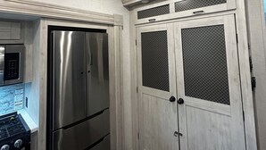 Une cuisine dotée d’appareils électroménagers en acier inoxydable, de meubles blancs et d’un luminaire suspendu.