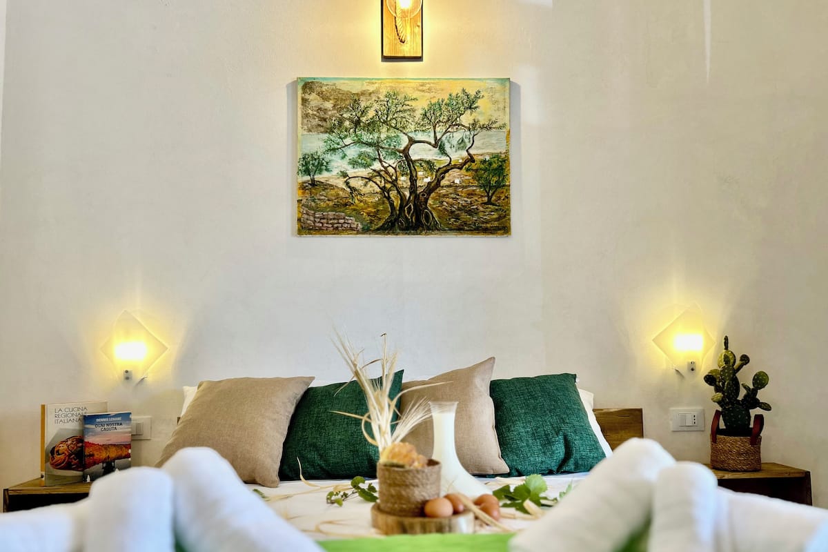 A neatly made bed with green bedding, two pillows, and a decorative centerpiece.