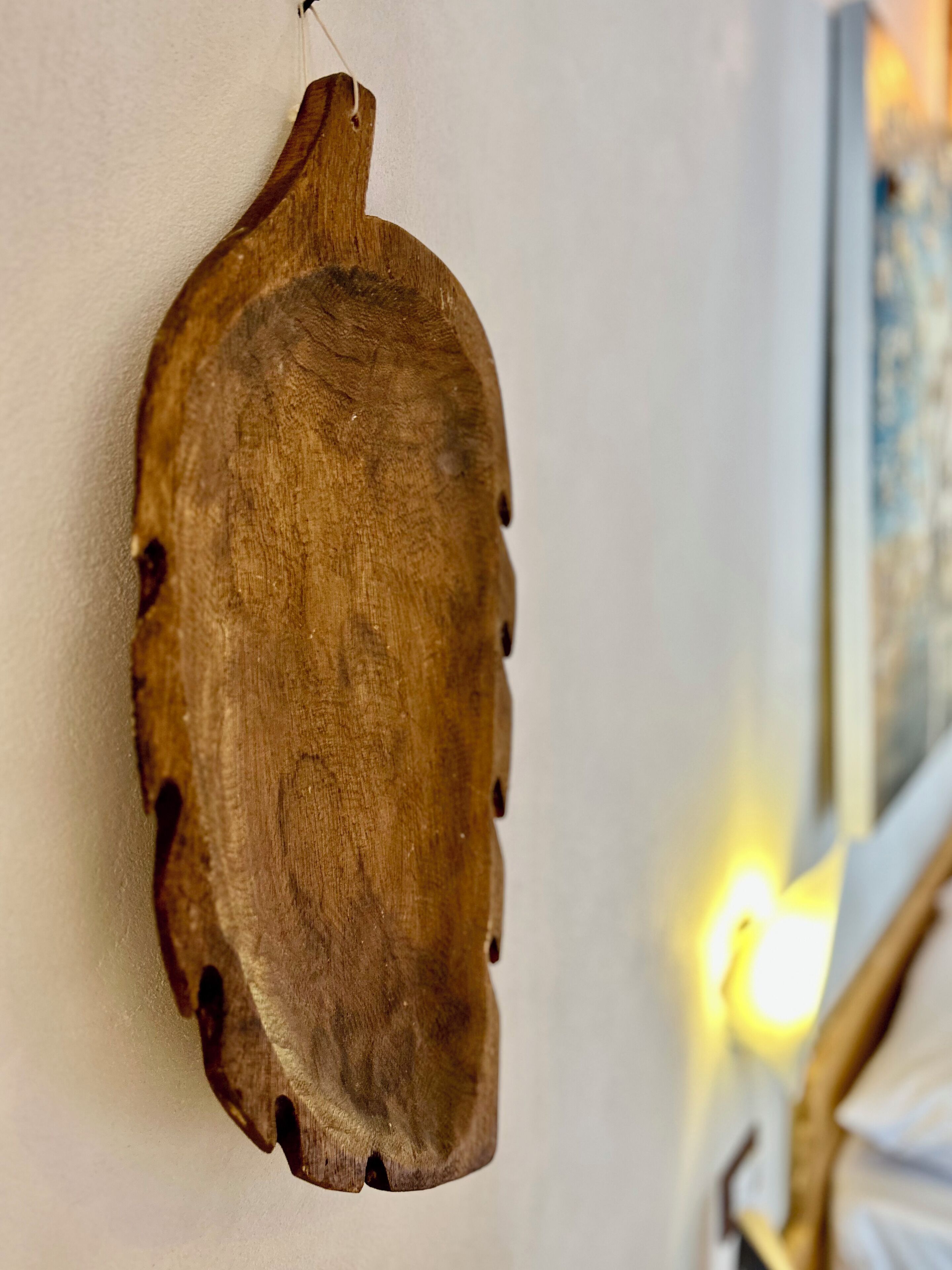 Un pannello decorativo in legno con finitura naturale e un foro nella parte superiore, probabilmente per appenderlo.
