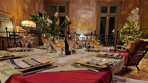 A formal dining room with a red tablecloth, multiple wine glasses, and a floral centerpiece. - Le Manoir de la Belle Endormie (Valréas)