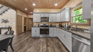 A modern kitchen with wooden ceiling, stainless steel appliances, and a granite countertop. - Smoky Cove Retreat-Close to all the action! (Sevierville)