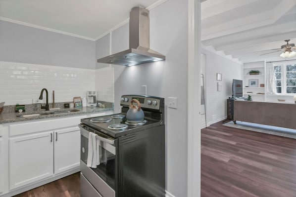 A modern kitchen with white cabinetry, a stainless steel stove, and a built-in range hood.