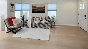A spacious living room with a high ceiling, a sofa, a chair, and a small table with a plant. - Luxury 3B house near Tec Hubs, High speed WiFi, Chef's Kitchen (San Jose)