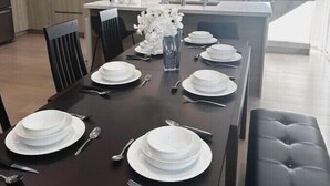 A modern kitchen with a central island, white appliances, and a dining area set for six with white plates and silverware. - Luxury 3B house near Tec Hubs, High speed WiFi, Chef's Kitchen (San Jose)