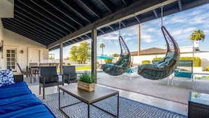 An outdoor patio with a covered area, wicker furniture, hanging chairs, and a pool in the background. - Pickleball-Basketball-HeatedPool-Spa-2 Primary BRs (Scottsdale)