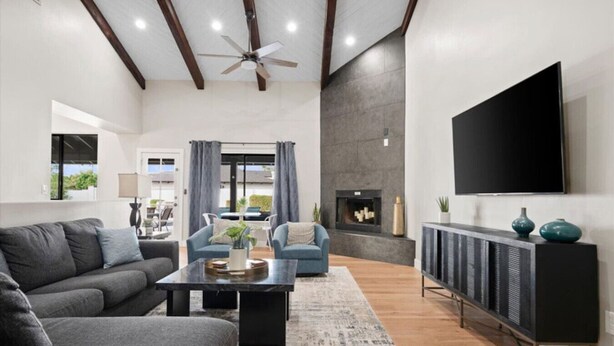 A modern living room with a fireplace, a large TV, and a ceiling fan. - Pickleball-Basketball-HeatedPool-Spa-2 Primary BRs (Scottsdale)