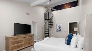 A bedroom with a bed, a TV on a dresser, a ceiling fan, and a spiral staircase. - Pickleball-Basketball-HeatedPool-Spa-2 Primary BRs (Scottsdale)