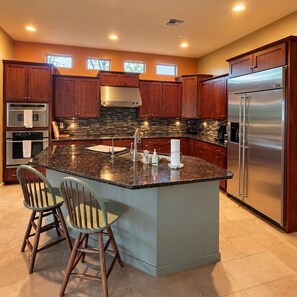 A kitchen with a central island, stainless steel appliances, and wooden cabinets.